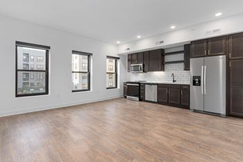 an empty kitchen with stainless steel appliances and dark wood cabinets at The Madison in Columbus, Ohio 43215